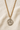St Dymphna 14KT Gold Filled round medal necklace on a beige fabric background