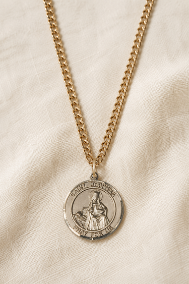 St Dymphna 14KT Gold Filled round medal necklace on a beige fabric background