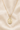 St Dymphna 14KT Gold Filled necklace with a pendant on a beige fabric background