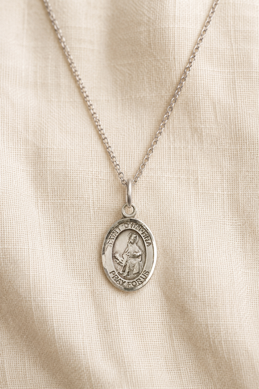 Sterling Silver St Dymphna pendant necklace on a beige fabric background