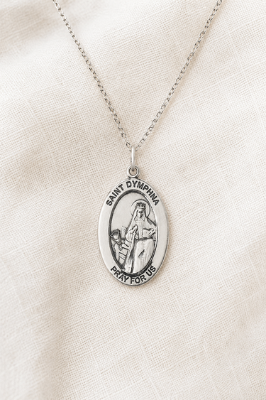 Sterling Silver pendant necklace with 'Saint Dymphna' on a beige fabric background