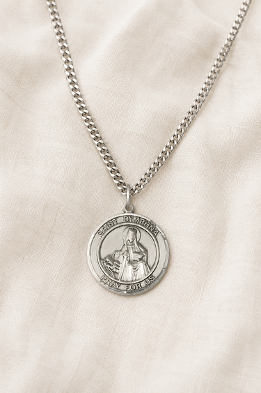 Sterling Silver St Dymphna medal necklace with a pendant on a beige fabric background