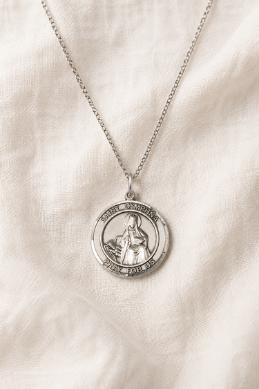 Sterling Silver St Dymphna round medal necklace for women with a pendant on a beige fabric background