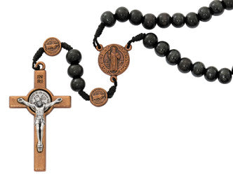 Close-up of copper St. Benedict crucifix on black wood bead rosary showing medal inscription detail
