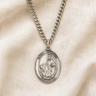 Sterling Silver St Dymphna medal necklace with a pendant on a beige fabric background