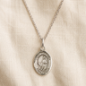 Sterling Silver St Dymphna pendant necklace on a beige fabric background