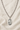 Sterling Silver St Dymphna necklace with a oval pendant on a beige fabric background and 24" chain