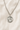Sterling Silver St Dymphna medal necklace with a pendant on a beige fabric background